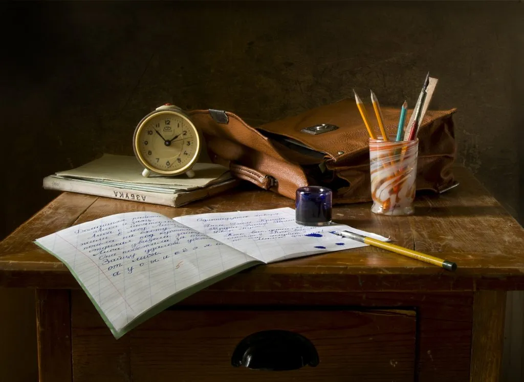 Una scrivania di legno con carta, penna e calamaio.